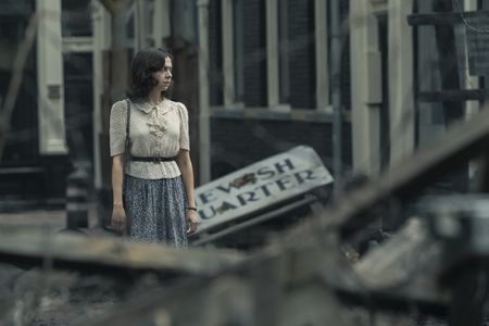 A SMALL LIGHT - Miep Gies, played by Bel Powley, walks through the derelict Jewish quarter as seen in A SMALL LIGHT. (Credit: National Geographic for Disney/Dusan Martincek)
