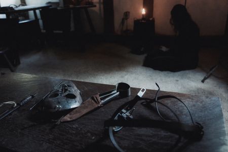 A table inside the prison cell holds multiple torture devices. Geillis Duncan is sitting in the background with her back to the table. (Dash Productions Services LTD/Antoan Ivanov)