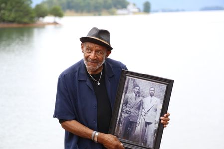 Vinnie Dabney holds a picture of his father, William Dabney. Dabney served as a corporal with the 320th Barrage Balloon Battalion on D-Day. (National Geographic/Shianne Brown)