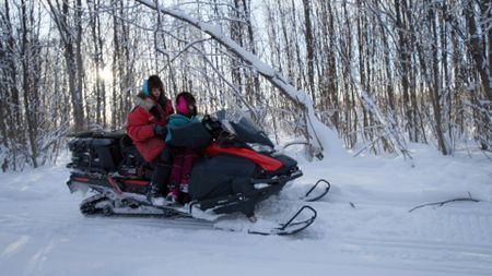 Ricko DeWilde travels by snowmobile with his daughter, Maya DeWilde while they set snares and explore the terrain. (BBC Studios/Ryan Walsh)