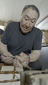 John Pingayak carving a bird out of wood for his grandchildren. (National Geographic/Matt Kynoch)