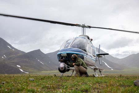 Director of photography Florian Schulz kneels down to check the GSS camera mounted at the front of the helicopter. (National Geographic for Disney/Andrew Moorwood)