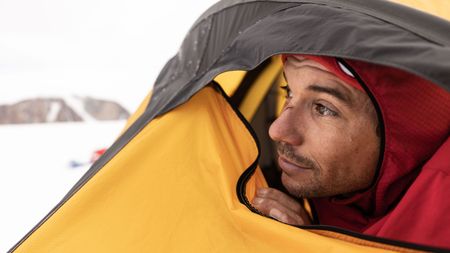Alex Honnold looks out across the Renland Icecap from his tent.  (photo credit: National Geographic/Pablo Durana)