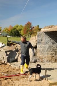 Ben Reinhold points next to his dog, Dax, as he is leveling out the wet concrete they are using for the sheep hut's flooring. (National Geographic)