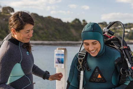 Assistant Raquel Trejo helps Dr. Alex Schnell gear up to dive with the Blue-ringed octopus.  (National Geographic for Disney/Harriet Spark)