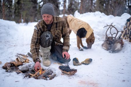 Johnny Rolfe adds kindling to a fire while he builds a box seat for his dog, Java. (BBC Studios Reality Production/Patrick Henderson)