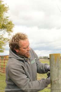 Ben Reinhold fixes one of the Pol family farm's animal pasture fence posts. (National Geographic)