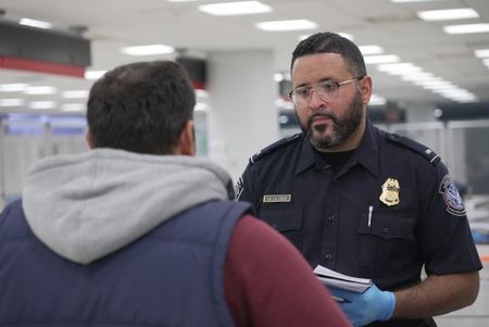 CBP Officer De La Cruz questions a traveler while they inspect the traveler's luggage at the Philadelphia International Airport in Philadelphia, Pa.  (National Geographic)