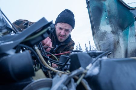 Johnny Rolfe fixes the carburetor on his snowmobile, and dethaws the frozen lines after it broke down in the wilderness. (BBC Studios Reality Productions/Tyler Colgan)