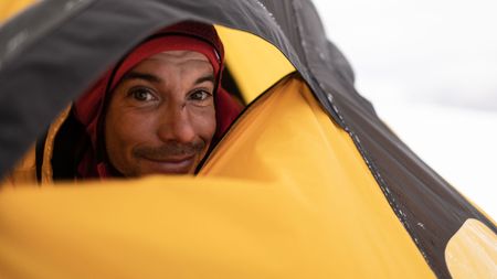Alex Honnold peering out of his tent at the Pool Wall base camp. (photo credit: National Geographic/Pablo Durana)