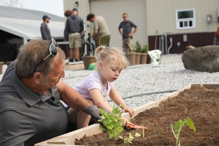 Art Reinhold helps Abigail Pol plant seeds at the Pol family's new garden, while Charles Pol and Ben's employees work on the Robot Garden system. (National Geographic)