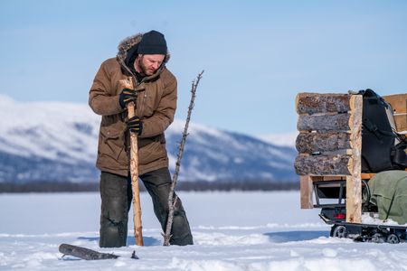 Johnny Rolfe checks his fishing lines underneath the ice. (BBC Studios Reality Productions/Patrick Henderson)