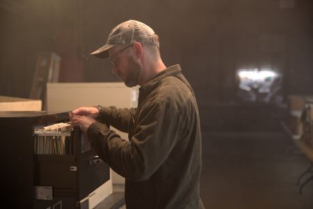 Journalist Dylan Taylor-Lehman is looks through case files during the production of "Cursed Gold: A Shipwreck Scandal." In 1989, maverick scientist Tommy Thompson stuns the world by recovering three tons of gold from a shipwreck deep in the Atlantic Ocean. What follows is a 30-year story of adventure, deception, and personal turmoil, taking him from venerated celebrity to infamous fugitive, and finally a defiant prisoner who refuses to give up his gold. (National Geographic)