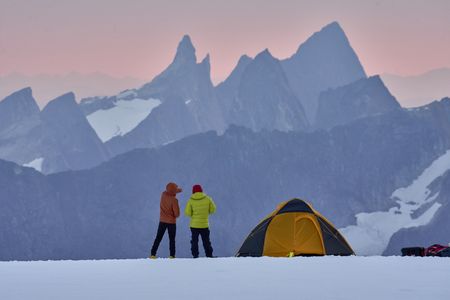 Alex Honnold and Tommy Caldwell looking out over the mountains at sunset, stood next to a tent at the Devil's Thumb campsite.  (National Geographic/Renan Ozturk)