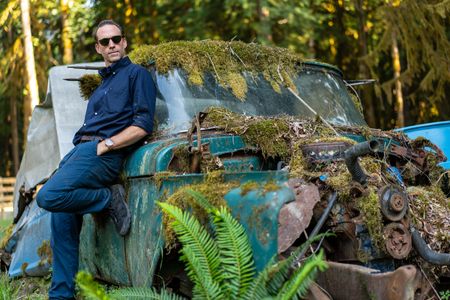 Joseph Fiennes poses for a portrait near an abandoned car. Amidst mountains and whale watching, Sir Ranulph Fiennes and his cousin Joseph Fiennes reflect on Ran’s epic life and his new challenge of life with Parkinson’s. (National Geographic)