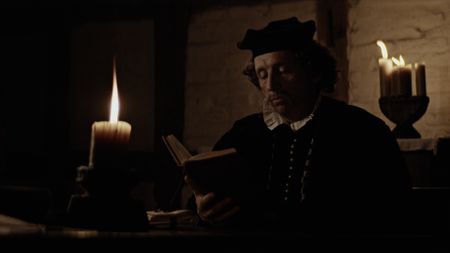 Pe Johann Von Schönenberg reading a book in candlelight. (Dash Pictures/Samuel Purcell, Oliver Watts)