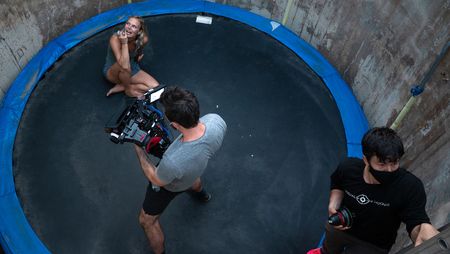 Angel Collinson sits on the trampoline as cinematographer Nick Kraus sets up the camera and assistant cameraperson Galen Murray holds a lens.   (National Geographic/Elena Gaby)