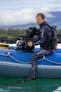 Bertie Gregory in dive gear with an underwater camera sitting on the edge of a small rib preparing to dive. (credit: National Geographic/Zubin Sarosh)