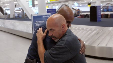 Chief Bowles gives Officer Bono a hug goodbye for his impending retirement from service, at the JFK International Airport, in New York.  (National Geographic)