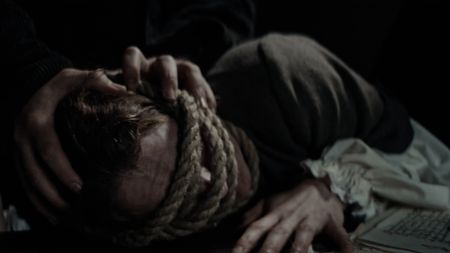 Agnes Sampson is being tortured for witchcraft. She is being held down, as rope is wrapped around her head and tightened. (Dash Pictures/Samuel Purcell, Oliver Watts)