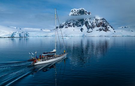 The Spirit of Sydney sailing against a backdrop of a mountain range in the Antarctic Peninsula. (credit: National Geographic/Bertie Gregory)