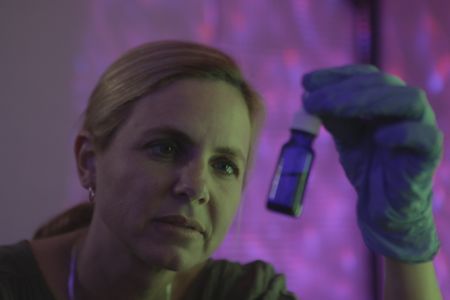 Mariana van Zeller holds a small bottle containing a substance. (Credit: National Geographic)