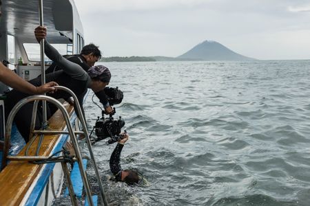 Dive crew hand an underwater camera system over the gunnels to cinematographer, Rory McGuinness, so he can film Algae octopus (Abdopus aculeatus) in Bunaken Marine Park.   (photo credit: National Geographic/Harriet Spark)