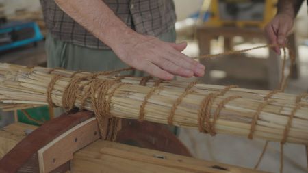 Maritime archaeologist Alessandro Ghidoni examines the beginnings of a reed crafted raft in Qantab, Oman. (Windfall Films)