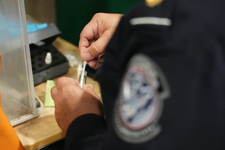 CBP Officer Bonilla is using a narcotics testing kit to identify the substance found smuggled in a suspect's vehicle in Calexico, Calif. (National Geographic)