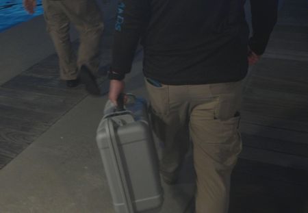 Two CBP Agents walk down a boat dock next to the ocean, with one agent holding a pelican briefcase in St Thomas, USVI. (Lucky 8 TV/Paul Taggart)