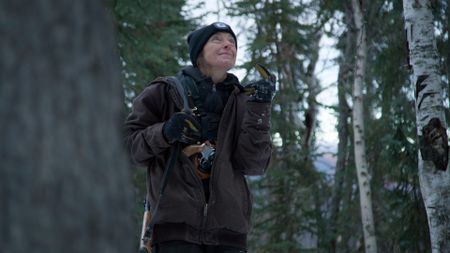 Denise Becker spots a marten in the trees while she checks her rabbit snares. (BBC Studios/Ben Mullin)