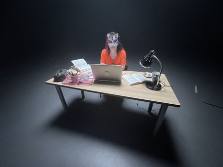 Member of the 4th Eye Corporation "Saturne" poses for a portrait while working at a desk for "Killer Lies: Chasing a True Crime Con Man," a documentary series about obsession and deception, following the unraveling of Stephane Bourgoin’s career as a best-selling author and serial killer expert. "Saturne" is a pseudonym; she chose to remain anonymous. (National Geographic/Ben Selkow)