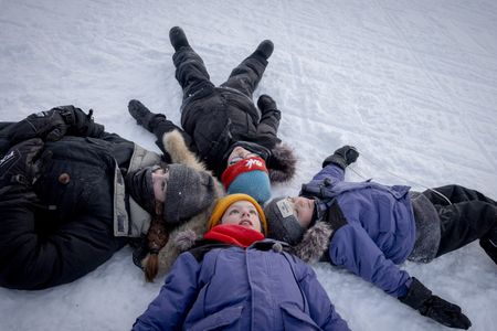 (Clockwise from left) Mia, Colin, Laurent, and Leo Pelletier lay in the snow and look up to the sky in Kuujjuaq, Canada. (Credit: National Geographic/Katie Orlinsky)