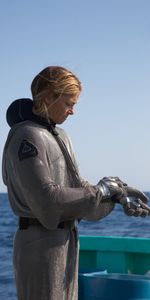 A diver in a suit putting on her gloves. (Big Wave Productions)