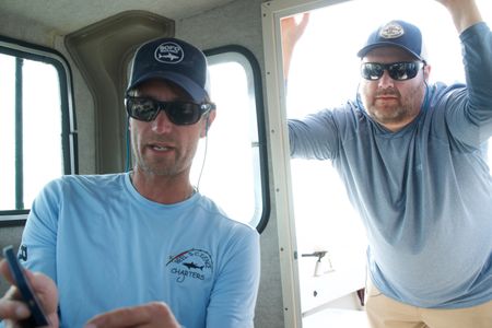 Capt. Greg Metzger and Dr. Tobey Curtis on the boat looking at a map of the Long Island Shore, discussing where the best place to fish might be. (National Geographic/Brandon Sargeant)