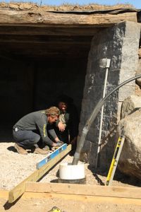 Ben Reinhold and Charles Pol use a spirit level and other tools to begin working on the sheep hut's new concrete floor. (National Geographic)