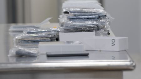 Multiple wrapped up iPhones are seen on an inspection table while CBP verifies a courier's manifest in Dulles, Va. (National Geographic)