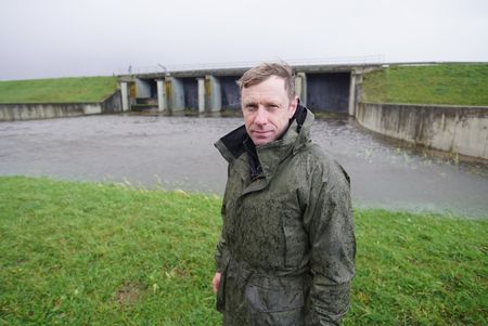 Andy Torbert stands outside a damn on the Ijssel Line. (National Geographic/Ciaran Henry)