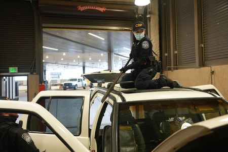 CBP Officers Hernandez and Hoffman work to dismantle the roof rack on a suspect's vehicle in search of smuggled drugs in Calexico, Calif. (National Geographic)