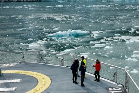 Aldo Kane, Leila Bouattaf, Olaf Dieckhoff, Oliver Dolan, and Ross Davison-Harmer standing together at bow of OceanXplorer looking at icy water. (National Geographic/Mario Tadinac)