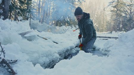 Billy shovels the snow while he is knee-deep in icy water.(Blue Ant Media/Tara Elwood)