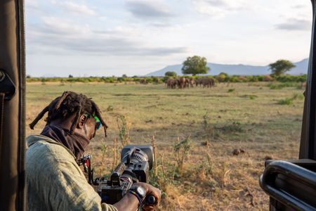 Camera Operator Manu Akatsa films a herd of elephants in Tsavo East National Park. (National Geographic for Disney/Maia Sherwood-Rogers)