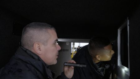 Two CBP officers inspect the luggage compartment of a coach bus for hidden contraband in Hidalgo, Texas. (National Geographic)