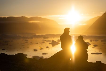 Aldo Kane and Adam Mike Kjeldsen look out at the low afternoon sun in Eastern Greenland.  (photo credit: National Geographic/Pablo Durana)
