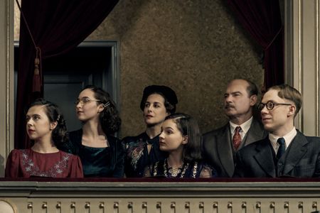 A SMALL LIGHT - The Gies and Frank families attend a performance at the Jewish Theater as seen in A SMALL LIGHT. (From left: Bel Powley as Miep Gies, Ashley Brooke as Margot Frank, Amira Casar as Edith Frank, Billie Boullet as Anne Frank, Liev Schreiber as Otto Frank, and Joe Cole as Jan Gies). (Credit: National Geographic for Disney/Dusan Martincek)