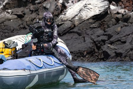 Bertie Gregory in dive gear with underwater camera, sitting on the edge of a small rib.  (credit: National Geographic/Zubin Sarosh)