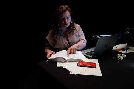 Member of the 4th Eye Corporation "Elora" consults materials during the production of "Killer Lies: Chasing a True Crime Con Man," a documentary series about obsession and deception, following the unraveling of Stephane Bourgoin’s career as a best-selling author and serial killer expert. "Elora" is a pseudonym; she chose to remain anonymous. (National Geographic/Ben Selkow)