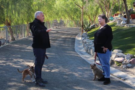 Cesar and Malinda holding dogs on leashes while talking. (National Geographic)