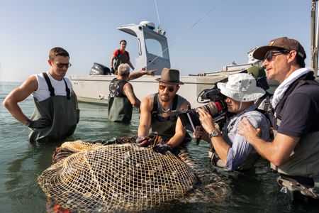 Behind-the-scenes of Antoni Porowski and Justin Theroux harvesting clams from the Po River alongside Simona and Germano. (National Geographic/Philippe Antonello)