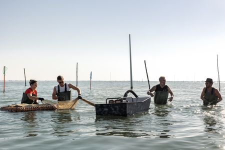 Simona, Antoni Porowski, Germano, and Justin Theroux work together to harvest clams from the Po River. (National Geographic/Philippe Antonello)